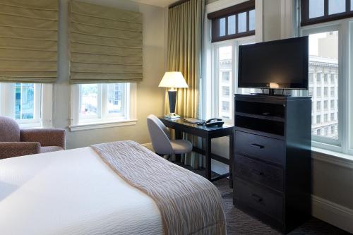 a hotel room with a bed and a desk with a television at The Sofia Hotel in San Diego