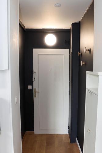 un couloir avec une porte blanche et une lumière au plafond dans l'établissement Studio design proche Défense-Paris, à Rueil-Malmaison