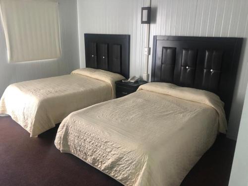 two beds in a hotel room with white sheets at BONITTO INN® Monterrey Norte in Monterrey