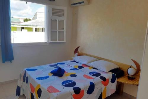 een slaapkamer met een bed met een kleurrijk dekbed en een raam bij Kaz a Man Fey in Petit-Canal