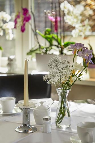 a table with a candle and flowers in a vase at Atrium Hotel Baden in Bad Krozingen