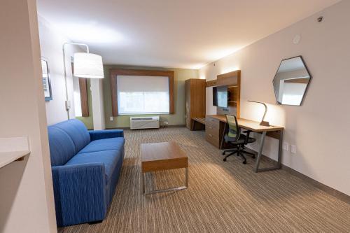 a living room with a blue couch and a desk at Holiday Inn Express & Suites Arlington North – Stadium Area by IHG in Arlington