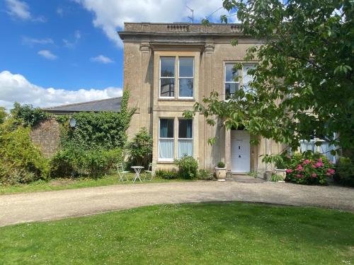 uma grande casa de tijolos com um relvado em frente em The Georgian Manor Apartment - Central Frome em Frome