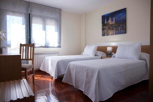 ビジャルバにあるLaros Pios Alojamiento 1のベッドルーム1室(白いリネンのベッド2台付)