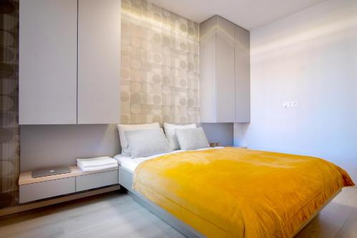 1 dormitorio con cama amarilla y armarios blancos en MF Casa Galerius Apartment, en Siófok
