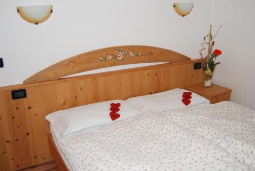 Una cama con poppers rojas en las almohadas en Residence Ciasa Alpe, en Vigo di Fassa