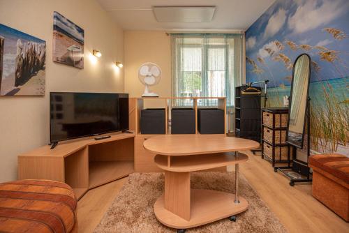 un soggiorno con un tavolo e una televisione di Centro Apartment a Palanga