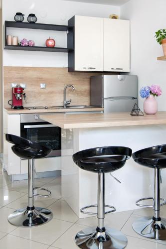 a kitchen with two black bar stools at a counter at Lavica Seaside Apartments, Podstrana in Podstrana