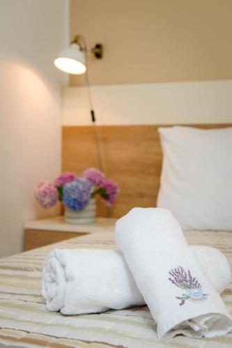 a bed with two towels and a pillow and flowers at Lavica Seaside Apartments, Podstrana in Podstrana