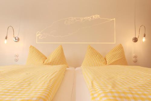 1 Schlafzimmer mit 2 Betten mit gelben und weißen Kissen in der Unterkunft Landhaus Bromm in Riezlern