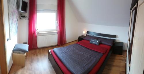 a bedroom with a bed with red curtains and a window at Private Zimmer bei der Weser-Ems-Halle in Oldenburg