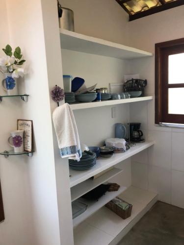 a kitchen with white shelves with dishes on them at Casa paradise perto da praia Guarajuba - BA in Camacari