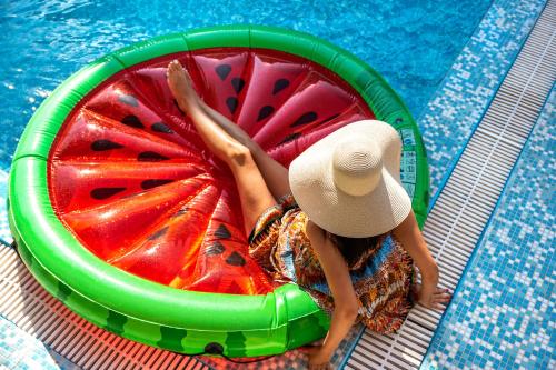 a woman laying on a watermelon raft in a pool at Luxury Mansion Rhodes in Ialyssos