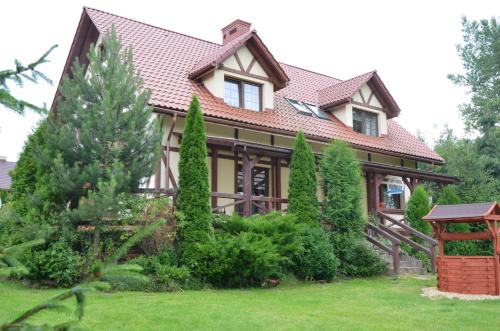 una casa con techo de baldosa y algunos árboles en Agroturystyka Leśny Potok en Fredropol