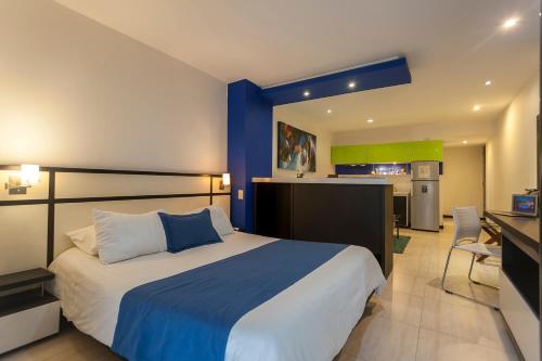 a bedroom with a large bed and a kitchen at Aqua Granada Hotel in Cali