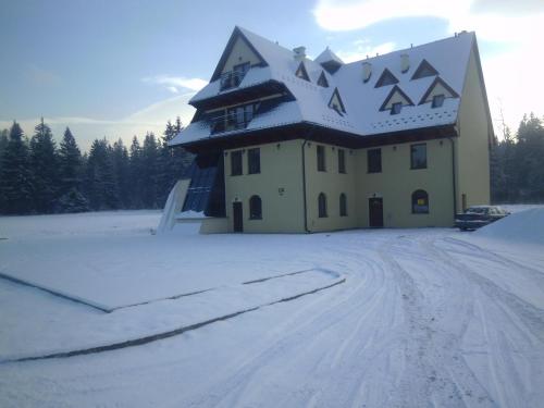 a building with a snow covered roof in the snow at Willa Pawlikowskich in Poronin