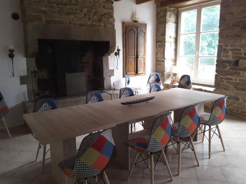 a table in a room with chairs and a fireplace at Le Château du Bonheur, Piscine, Sauna et Jacuzzi in Le Loreur