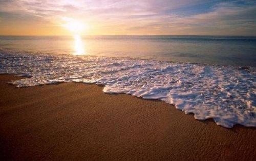 a beach with the sun rising over the ocean at Le Château du Bonheur, Piscine, Sauna et Jacuzzi in Le Loreur