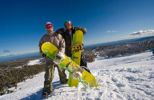 two men standing on top of a snow covered slope holding a snowboard at Walhalla's Star Hotel in Walhalla