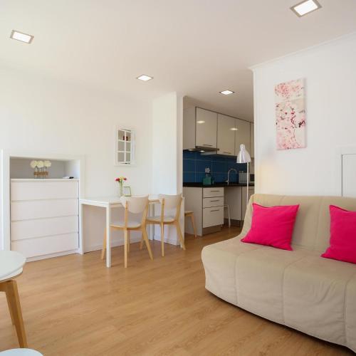 a living room with a couch and a table with pink pillows at Apartamentos com Historia in Coimbra