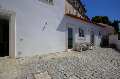 a white building with chairs and a patio at Apartamentos com Historia in Coimbra