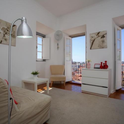 a living room with a bed and a table and a window at Apartamentos com Historia in Coimbra