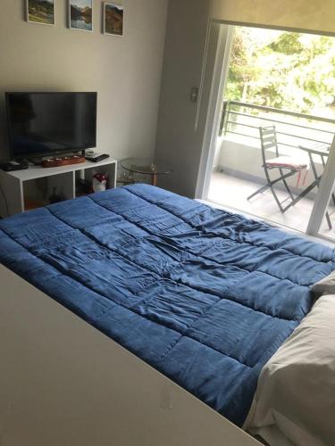 a bed with a blue comforter in a bedroom at Nuevo y muy bien equipado departamento en Pucón in Pucón
