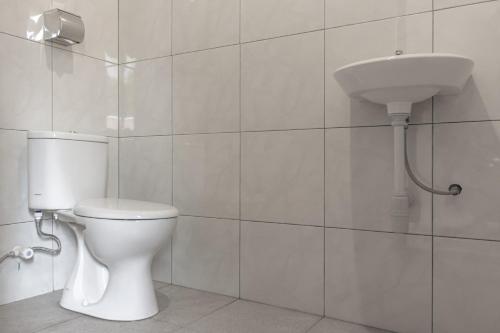 a white bathroom with a toilet and a sink at Hotel Niki in Jembrana