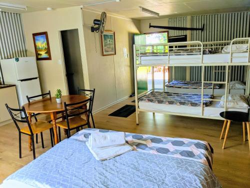 a bedroom with two bunk beds and a table and a dining room at Woolshed Eco Lodge in Hervey Bay