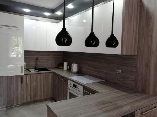 a kitchen with wooden cabinets and black pendant lights at Apartament Nadmorski in Kołobrzeg
