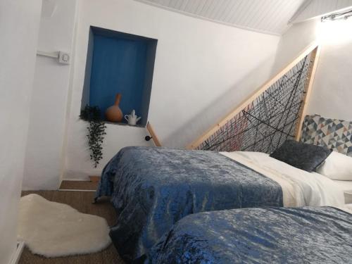 a bedroom with two beds and a window with blue curtains at la casita in Le Bourg-dʼOisans