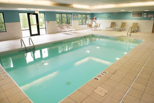 エルクハートにあるHoliday Inn Express Hotel & Suites Elkhart-South by IHGの建物の中に椅子とテーブルが置かれた大きなプール