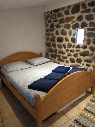 a bed in a room with a stone wall at La maison D'Orée in Polignac