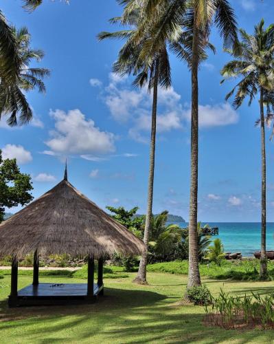 a straw hut on the beach with palm trees at Shantaa Resort, Kohkood in Ko Kood