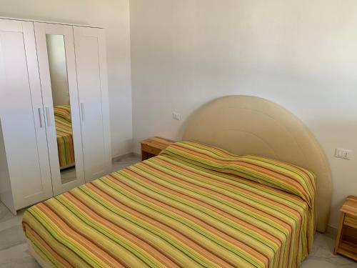 a bedroom with a bed with a striped blanket at Stabilimento Balneare Città Giardino - Casa Vacanza in Viareggio
