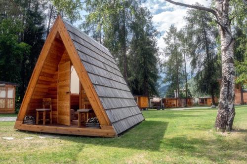 a frame cabin with a pitched roof in a yard at I Larici Camping Lodge in Ossana