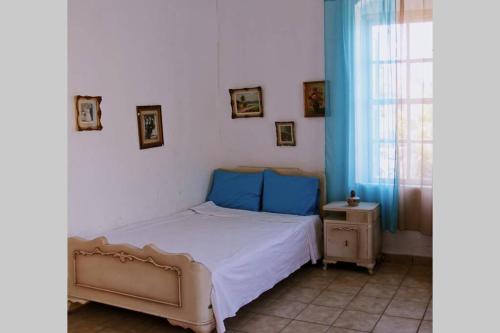 a bedroom with a bed with blue pillows and a window at Iliana's courtyard in Evdilos