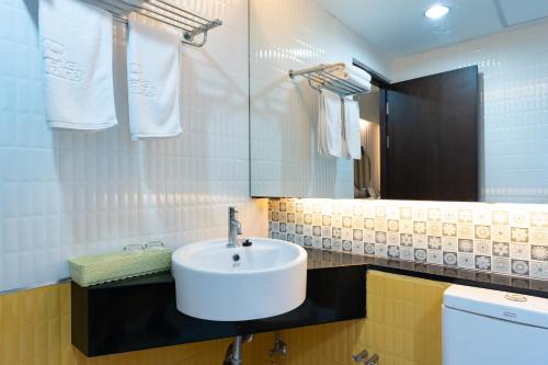 y baño con lavabo blanco y espejo. en Royal Delight Hotel en Bangkok