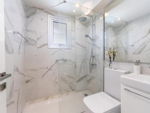 a white bathroom with a shower and a toilet at Mackenzie Leo Seafront Suite in Larnaka