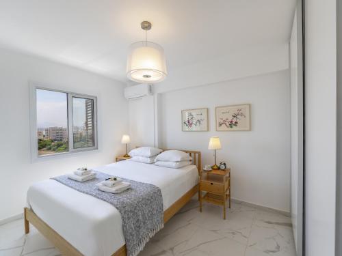a white bedroom with two beds and a table at Mackenzie Leo Seafront Suite in Larnaka