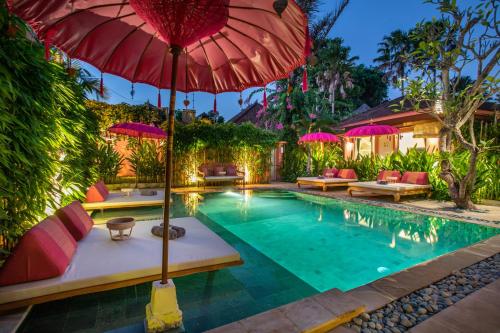una casa y una piscina con sombrilla y sillas rojas en PinkPrivate Sanur - for Cool Adults Only, en Sanur