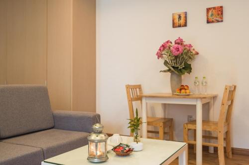 a living room with a couch and a table with flowers at HNC Premier Hotel & Residences in Hanoi