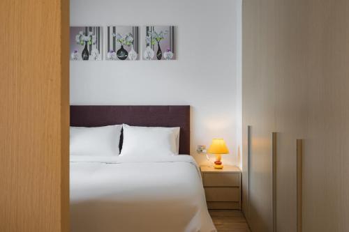 a bedroom with a white bed and a table with a lamp at HNC Premier Hotel & Residences in Hanoi