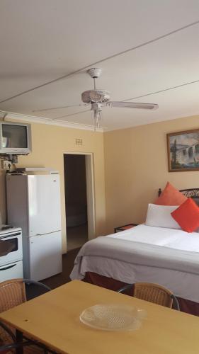 Zimmer mit einem Bett, einem Kühlschrank und einem Tisch in der Unterkunft Amberlight Self Catering Accommodation in Krugersdorp
