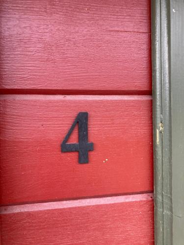 une porte en bois rouge avec un numéro quatre sur elle dans l'établissement Asplunda Gård,Kolmården, stuga nr 4, à Kolmården