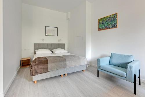 a bedroom with a bed and a blue chair at Grand Apartments - Studio Apartment 50 m from Monte Cassino in Sopot
