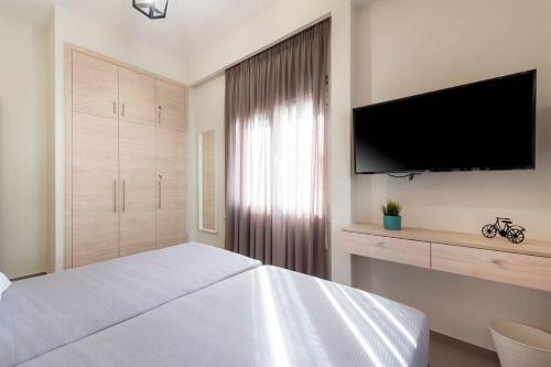 a bedroom with a large white bed and a flat screen tv at Fofi’s Elegant Home in Kos Town