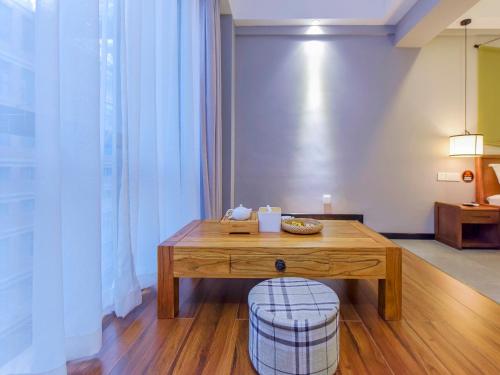 a wooden table with a stool in a room at Chongqing Ouranjian Lake View Guesthouse in Chongqing