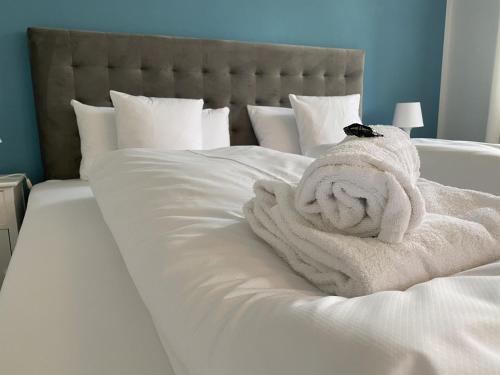 een wit bed met een stapel handdoeken erop bij Apartment SEEnsucht - Tolle Lage, nah am See, perfekt für Familien in Schliersee