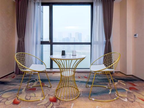 two chairs and a table in front of a window at Chongqing Ouranjian Lake View Guesthouse in Chongqing